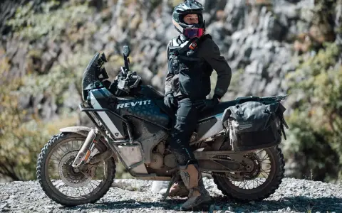 Motociclista con chaqueta REV'IT! y equipo de aventura, listo para aprender como lavar chaqueta de moto después de un viaje polvoriento.