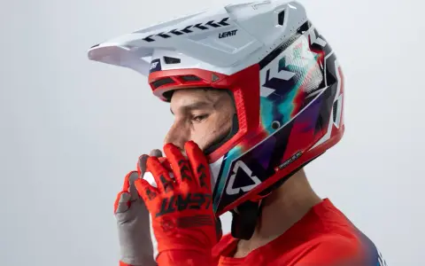 Hombre con casco de moto para usar con gafas graduadas, guantes rojos y jersey deportivo.