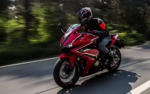 Motociclista en moto deportiva roja, disfrutando de la carretera con potencia máxima A2.