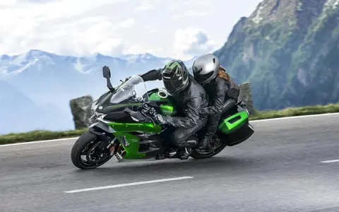 Pareja en una moto deportiva verde y negra, disfrutando de un viaje por carretera entre montañas. ¡Las mejores motos deportivas para aventuras!