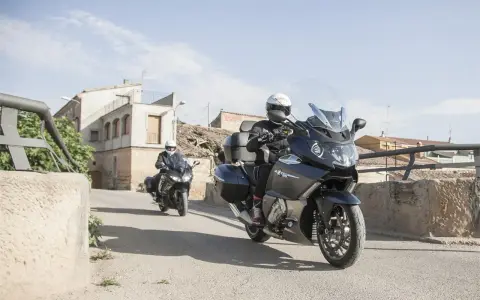 Dos motociclistas en sus Benelli 1200 GT recorren un pueblo soleado.