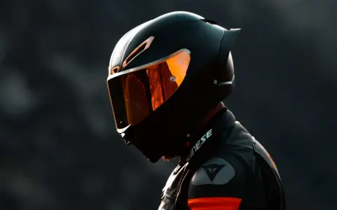Motociclista con su primer casco de moto, visera naranja reflejando la luz.