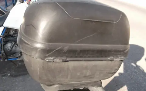 Baúl negro de moto, con marcas de uso. ¿Será que alguien pensó en pintar el baúl de la moto para darle un nuevo look?