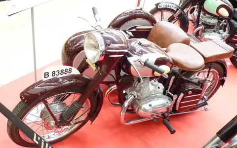 Moto Derbi clásica con sidecar, color burdeos, con asientos de cuero marrón y detalles cromados.