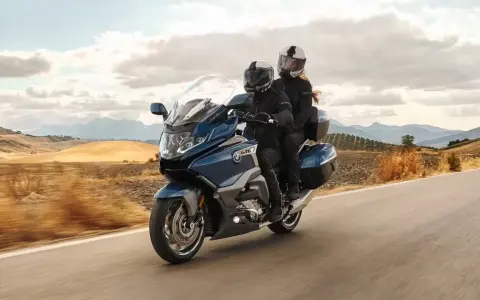 Pareja disfrutando de un viaje en moto cómoda por un paisaje rural.