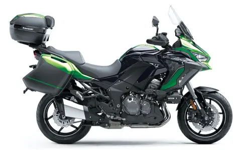 Una moto crossover Kawasaki Versys negra y verde, lista para la aventura con maletas laterales y baúl.