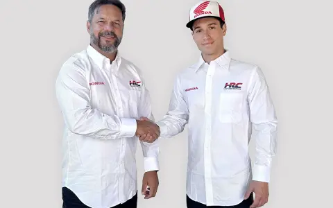 Dos hombres con camisas blancas de Honda y HRC Racing se dan la mano. Uno lleva una gorra de Honda.
