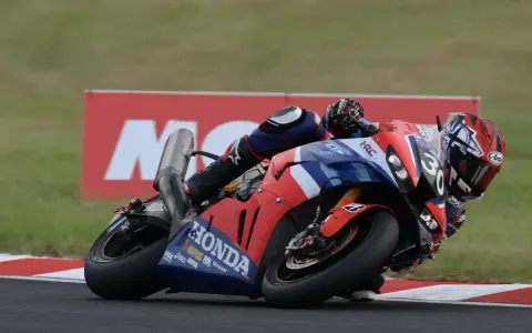 Piloto en moto Honda roja y azul inclinado en curva durante las 8 horas de Suzuka.