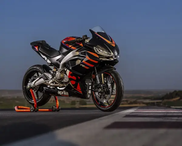 Aprilia RS 457 ficha técnica: una deportiva negra con detalles naranjas y rojos, lista para la acción en pista.