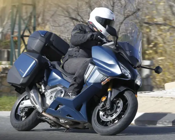 Motociclista en Honda Forza 750 azul con maletas, ideal para viajes. Conoce su honda forza 750 ficha técnica.