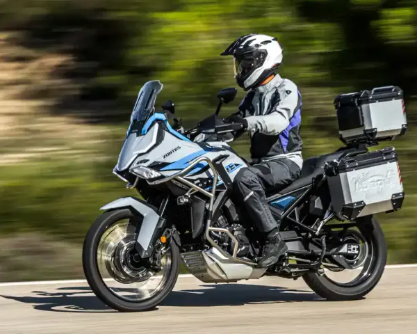 Motociclista con casco blanco y equipo de aventura sobre una moto Zontes, lista para explorar caminos. Motos adventure A2 perfectas para tu próxima travesía.