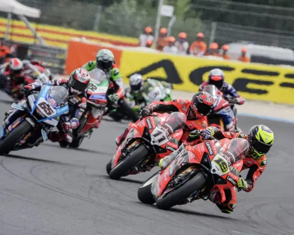 Motociclistas compiten en una carrera, con el número 65 en primer plano. El sbk calendario se acerca.