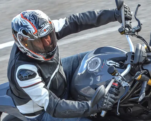 Motociclista con casco Suomy, con diseño llamativo, en una moto deportiva. Las opiniones sobre cascos Suomy son positivas.