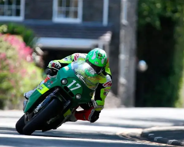 Victor López compite en la Isla de Man con su moto verde número 17, inclinado en una curva cerrada.
