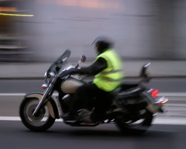 Motociclista con chaleco reflectante amarillo brillante, cumpliendo la norma de que es obligatorio llevar chaleco reflectante en la moto.
