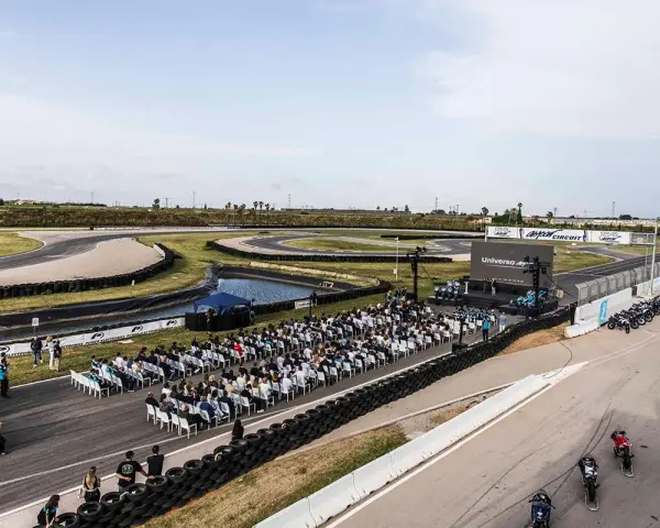 Evento en el aspar circuit con público sentado frente a un escenario. Motos alineadas en la pista.