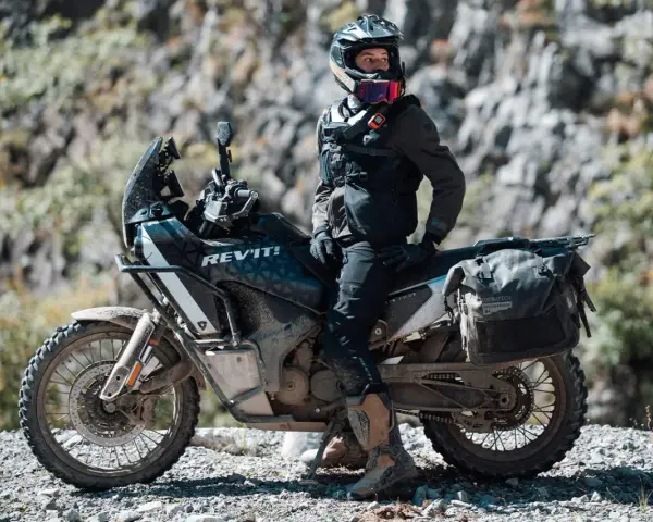 Motociclista con chaqueta REV'IT! y equipo de aventura, listo para aprender como lavar chaqueta de moto después de un viaje polvoriento.