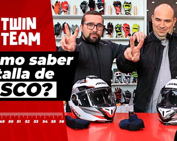 Dos hombres sonríen y muestran cascos de moto, listos para probar tallas. Fondo con guantes y cinta métrica.