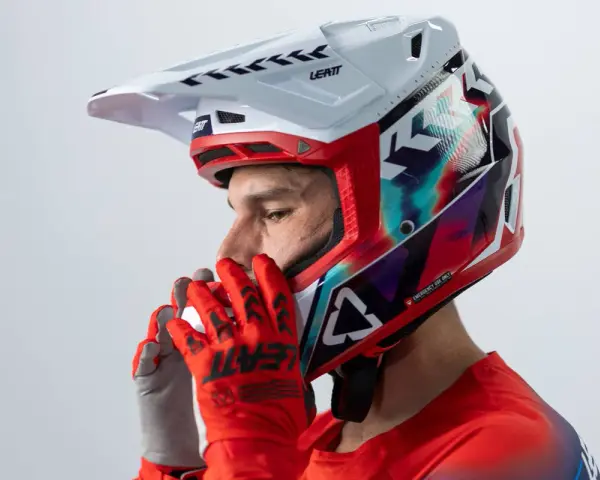 Hombre con casco de moto para usar con gafas graduadas, guantes rojos y jersey deportivo.