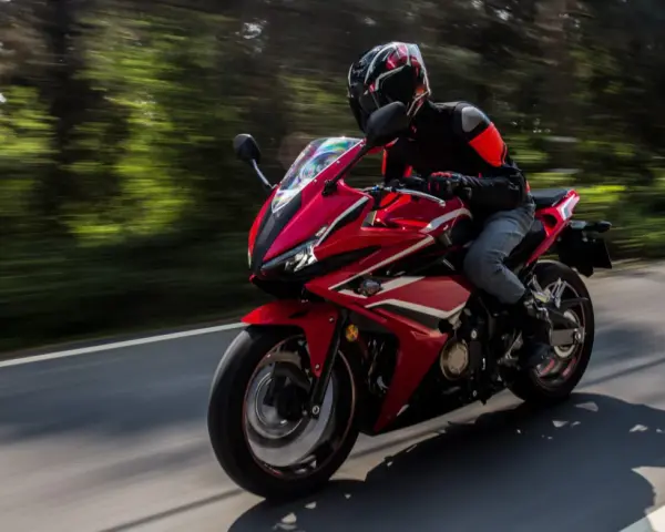 Motociclista en moto deportiva roja, disfrutando de la carretera con potencia máxima A2.