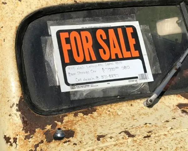Coche antiguo a la venta, con cartel "FOR SALE". Para saber si una moto tiene cargas, revisa su historial.