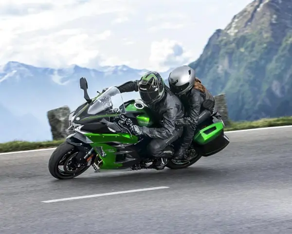 Pareja en una moto deportiva verde y negra, disfrutando de un viaje por carretera entre montañas. ¡Las mejores motos deportivas para aventuras!