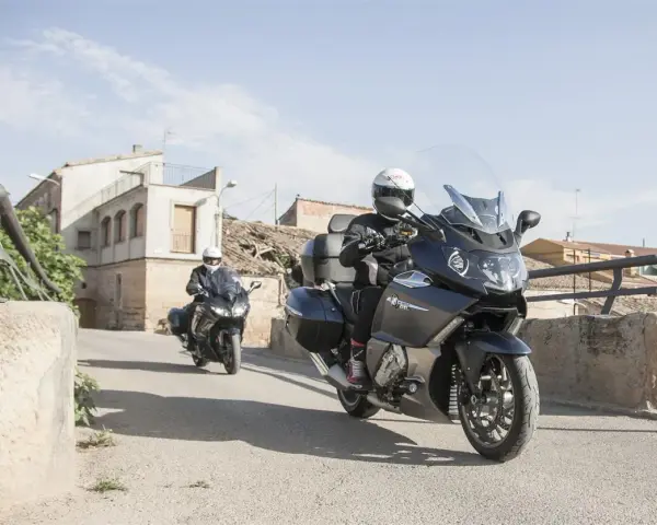Dos motociclistas en sus Benelli 1200 GT recorren un pueblo soleado.
