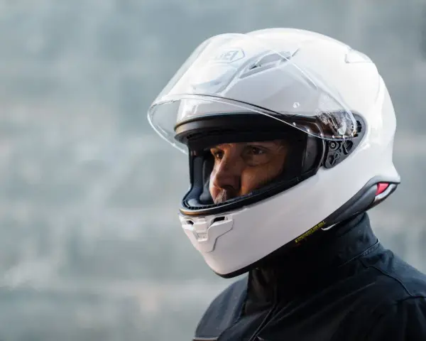 Hombre con casco blanco Shoei NXR 2. Su peso es ideal para largas rutas.
