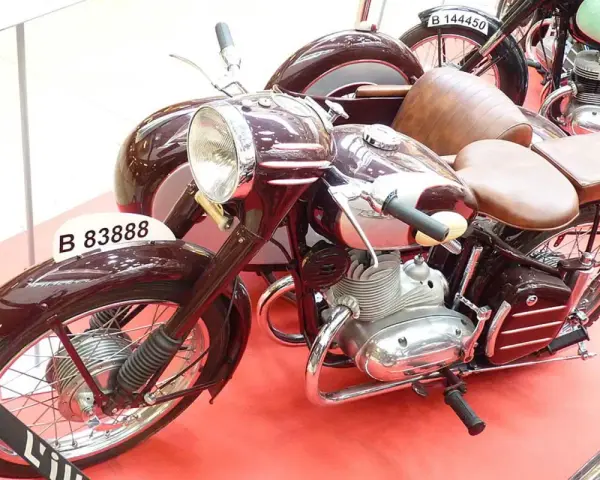 Moto Derbi clásica con sidecar, color burdeos, con asientos de cuero marrón y detalles cromados.