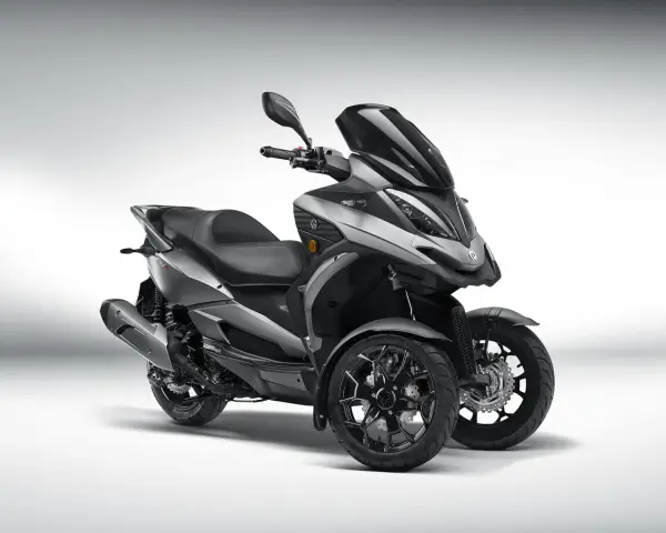 Triciclo gris moderno, estilo deportivo, con tres ruedas. El **Quadro QV3** es un vehículo ágil y seguro, ideal para sortear el tráfico urbano sin **problemas**.