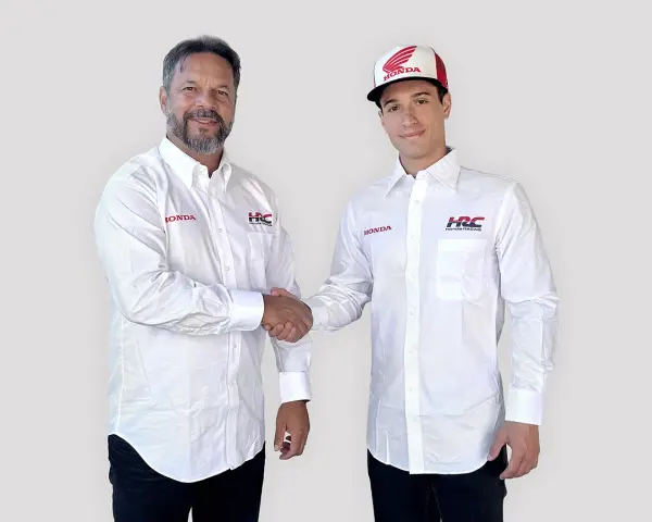 Dos hombres con camisas blancas de Honda y HRC Racing se dan la mano. Uno lleva una gorra de Honda.