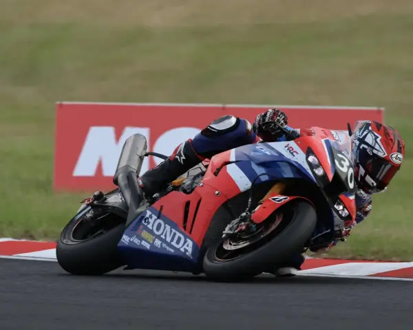 Piloto en moto Honda roja y azul inclinado en curva durante las 8 horas de Suzuka.