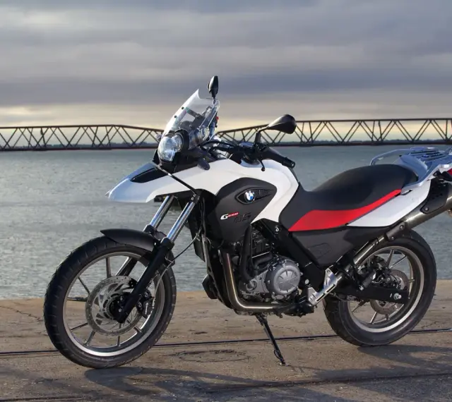 Moto BMW G 650 GS, ideal para el carnet A2, aparcada junto a un puente y el mar.