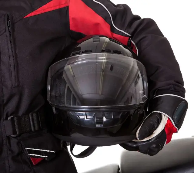 Motociclista con chaqueta negra y roja, guantes y casco con visor transparente. El pinlock casco garantiza una visión clara.