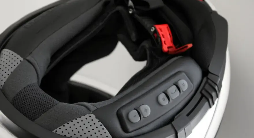 Detalle del interior de un casco modular, mostrando el proceso para instalar intercomunicador. Botones de control visibles.