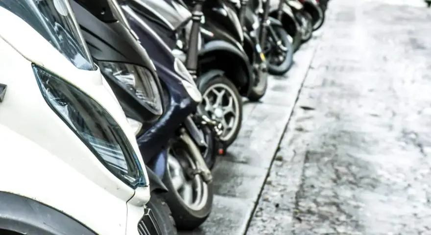 Una fila de motos aparcadas en la acera. Se puede aparcar la moto en la acera, facilitando el tránsito peatonal.