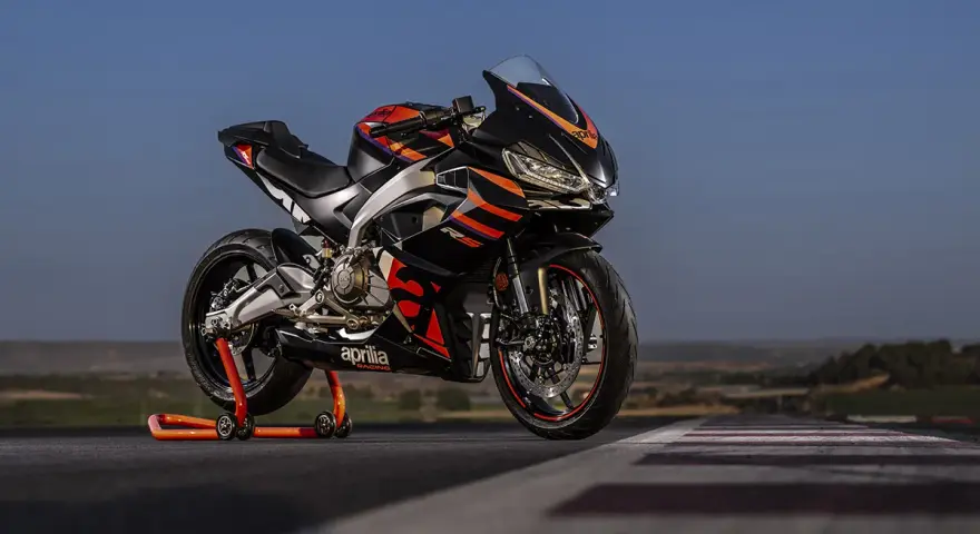Aprilia RS 457 ficha técnica: una deportiva negra con detalles naranjas y rojos, lista para la acción en pista.