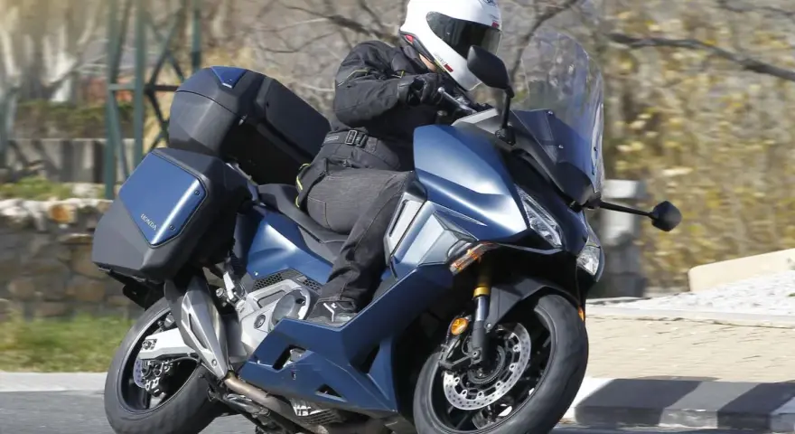 Motociclista en Honda Forza 750 azul con maletas, ideal para viajes. Conoce su honda forza 750 ficha técnica.