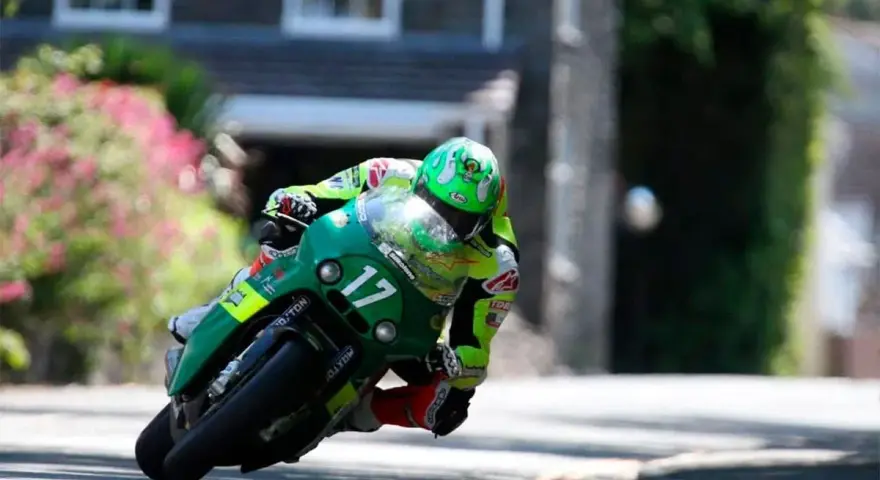 Victor López compite en la Isla de Man con su moto verde número 17, inclinado en una curva cerrada.