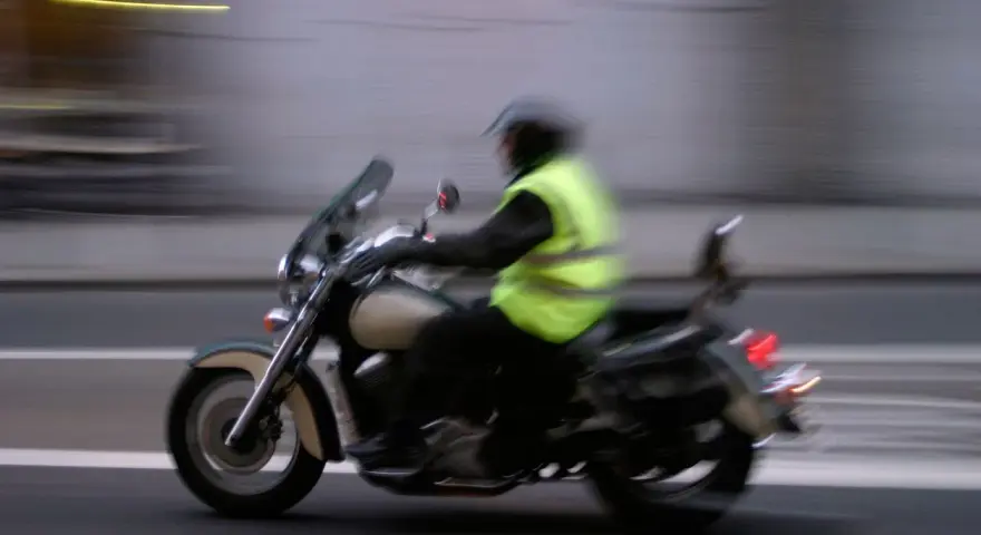 Motociclista con chaleco reflectante amarillo brillante, cumpliendo la norma de que es obligatorio llevar chaleco reflectante en la moto.