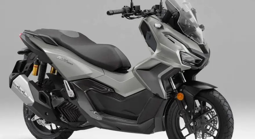 Scooter gris Honda ADV 160 con parabrisas alto y asiento doble.