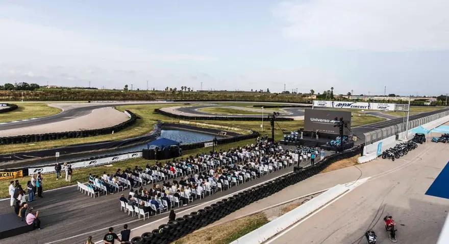 Evento en el aspar circuit con público sentado frente a un escenario. Motos alineadas en la pista.