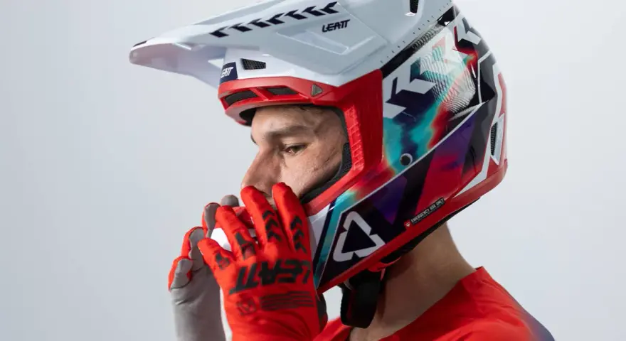 Hombre con casco de moto para usar con gafas graduadas, guantes rojos y jersey deportivo.