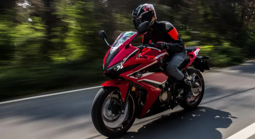 Motociclista en moto deportiva roja, disfrutando de la carretera con potencia máxima A2.