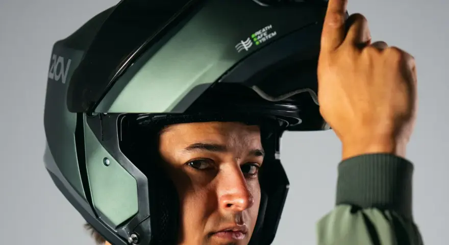 Hombre ajustando su casco integral o modular, de color verde militar, con sistema de ventilación.