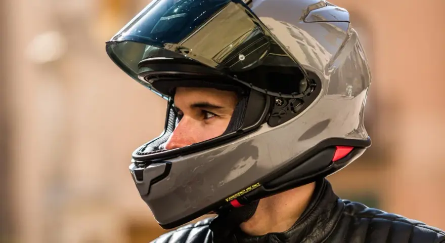 Hombre con casco de moto gris brillante. ¿Cuánto pesa un casco de moto? Este modelo parece ligero y aerodinámico.