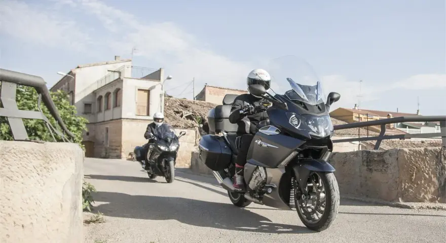 Dos motociclistas en sus Benelli 1200 GT recorren un pueblo soleado.