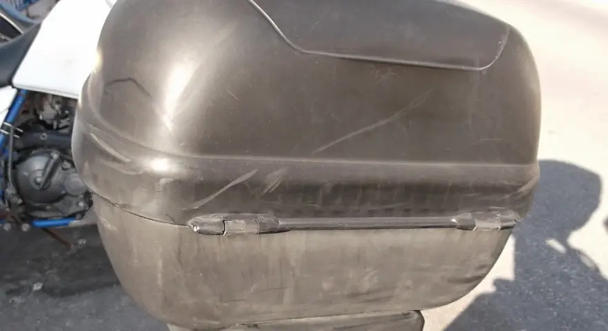 Baúl negro de moto, con marcas de uso. ¿Será que alguien pensó en pintar el baúl de la moto para darle un nuevo look?