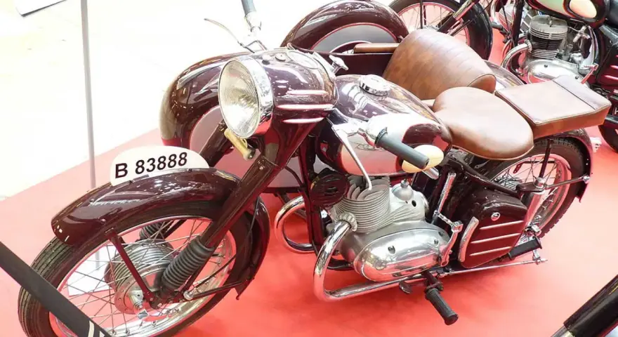Moto Derbi clásica con sidecar, color burdeos, con asientos de cuero marrón y detalles cromados.