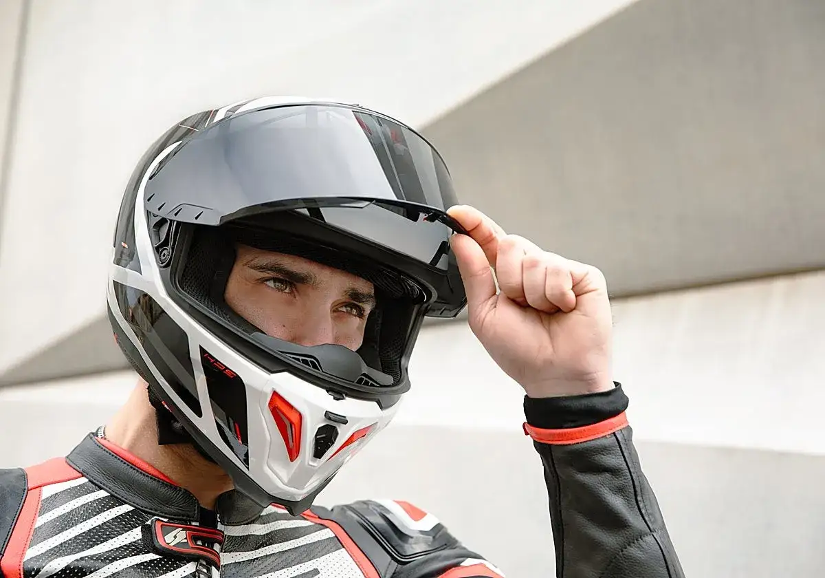 Motorista ajusta su casco, cumpliendo la normativa de cascos moto. Dise&ntilde;o moderno y seguro.